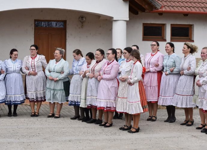 Women in colorful traditional folk dresses gather outdoors, showcasing cultural attire and community celebration.